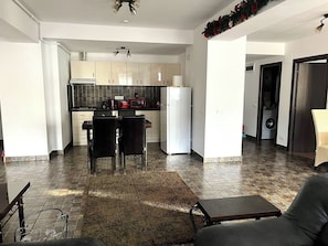 A modern kitchen with white cabinets, a refrigerator, and a microwave. There is a dining area with a table and chairs. - Sofia's Dream Retreat (Sinaia)