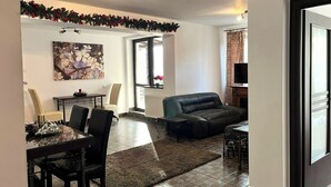 Un salon comprenant un canapé, une table à manger avec des chaises, une cheminée et un téléviseur.