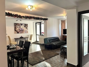 Ein Wohnzimmer mit einer Couch, einem Esstisch mit Stühlen, einem Kamin und einem Fernseher.