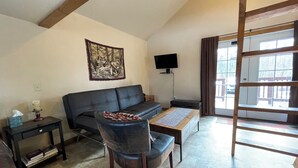 A living room with a sofa, a chair, a coffee table, a TV, and a painting on the wall. - Peaceful 1-bedroom cabin in charming Talkeetna perfect for getaway (Talkeetna)