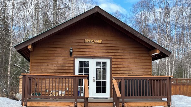 A wooden cabin with a number '14455' on the front, a white door, and a small porch with a wooden railing. - Peaceful 1-bedroom cabin in charming Talkeetna perfect for getaway (Talkeetna)