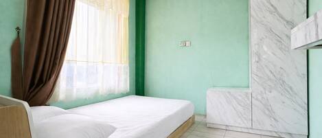 Une pièce avec un lit, une fenêtre avec des rideaux, un mur en marbre et un mur vert.