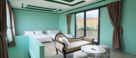 A hotel room with a sofa, two beds, a balcony, and a dining area.