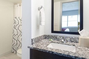 A bathroom with a granite sink, a towel rack, a mirror, and a shower curtain. - Miami Beach 2BR | Beachfront Pool Retreat (Surfside)