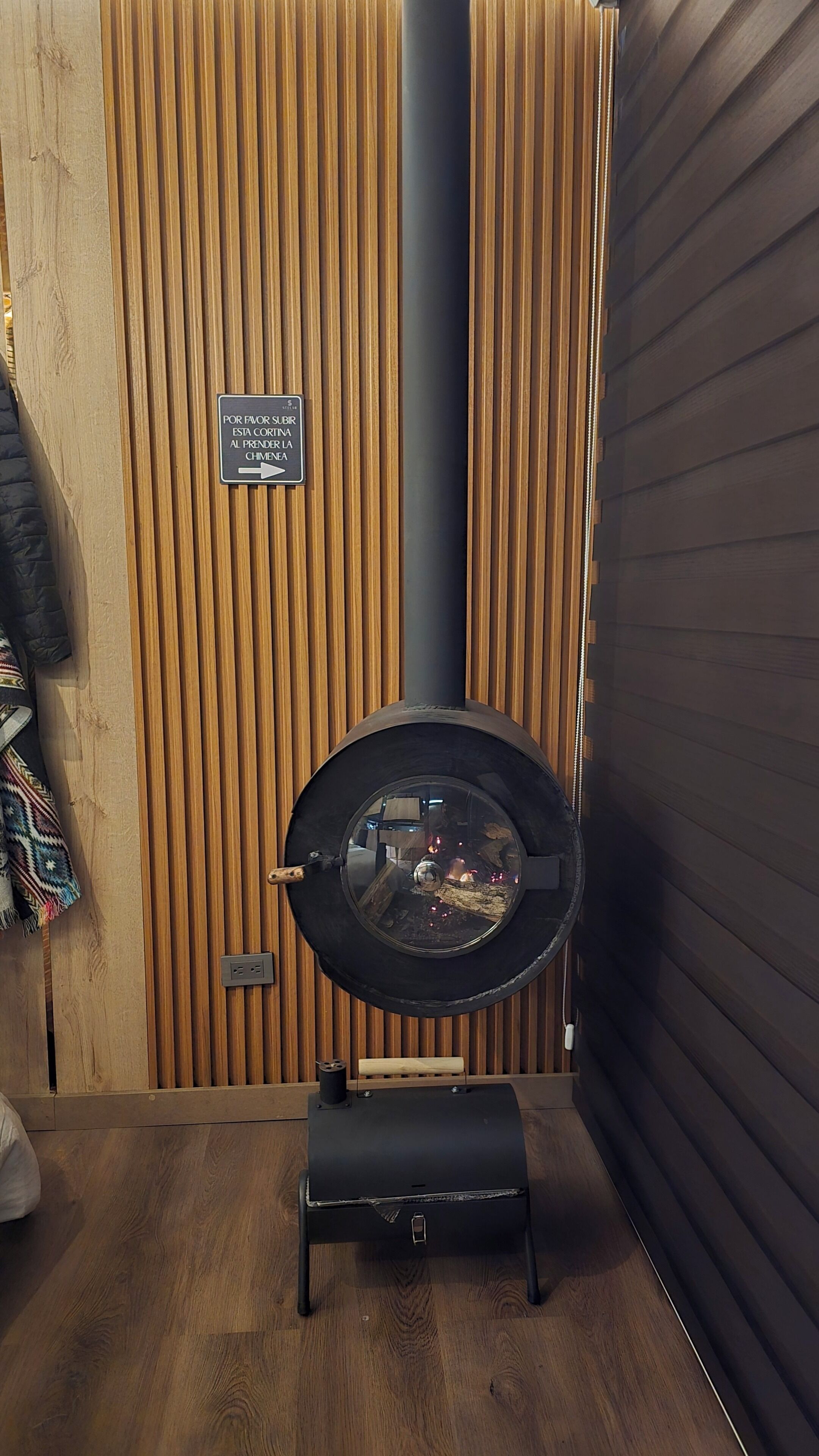 Ein raum mit Holzwänden, einem Kamin, einem Schild, das die Position des Kamins anzeigt, und einem kleinen Holzschemel davor.