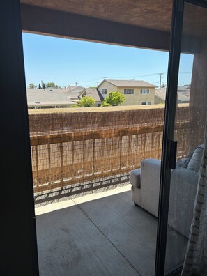 A balcony with a view of a residential area, a wooden fence, and a sofa. - Huntington Beach Condo (Huntington Beach)