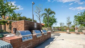 An outdoor barbecue area with brick walls and multiple grills. - Huntington Beach Condo (Huntington Beach)