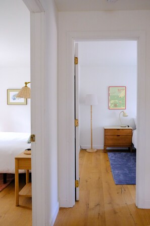 Una habitación con cama, mesita de noche, lámpara y un cuadro en la pared.
