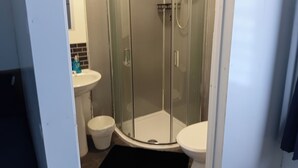 A bathroom with a glass-enclosed shower, a white sink, and a toilet. - Studio Sleeps 2 with Parking (Oldbury)