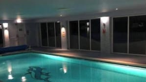 Una piscina interior con superficie de agua cristalina, un trampolín y suelo de baldosas.