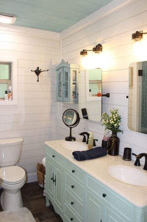 A bathroom with a white toilet, a sink with a mirror, and a vanity with drawers.