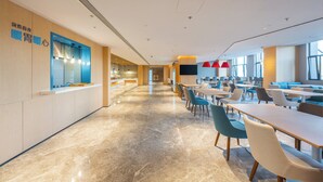 A spacious, modern dining area with long tables and chairs, a kitchen area with blue cabinets, and large windows providing natural light. - Holiday Inn Express Xinji City Center an IHG Hotel (Shijiazhuang)
