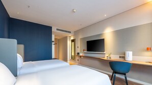 A modern hotel room with a large bed, a desk with a flat-screen TV, a chair, and a small table with a vase of flowers. - Holiday Inn Express Xinji City Center an IHG Hotel (Shijiazhuang)