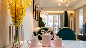 A dining area with a table set for tea, a vase of yellow flowers, and a teal chair.