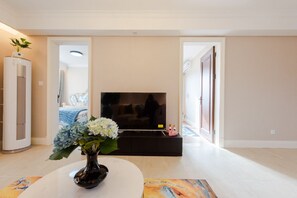 A living room with a TV, a vase with flowers, and a sofa.