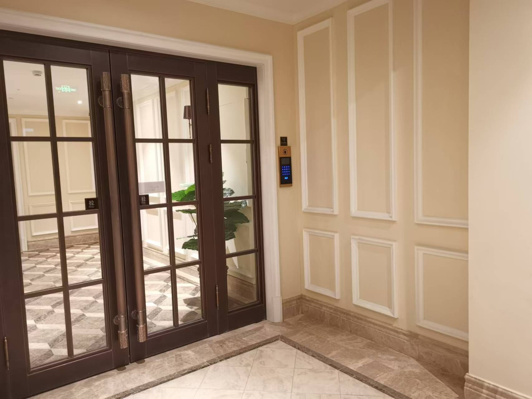 En hotellentrél med en mörk trädörr, ett kodlås och ett klinkergolv.
