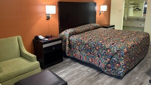 Una habitación de hotel con cama, mesita de noche, teléfono, silla y una pequeña mesa.