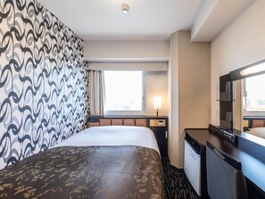 Une chambre d’hôtel avec un lit, un bureau, une chaise, une télévision et une fenêtre avec des rideaux.
