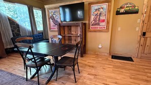 Ein Essbereich mit Holztisch und Stühlen, einem Deckenventilator und einem Wandfernseher.