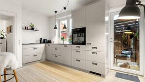 Una cocina moderna con armarios blancos, un refrigerador negro y un ventanal grande.