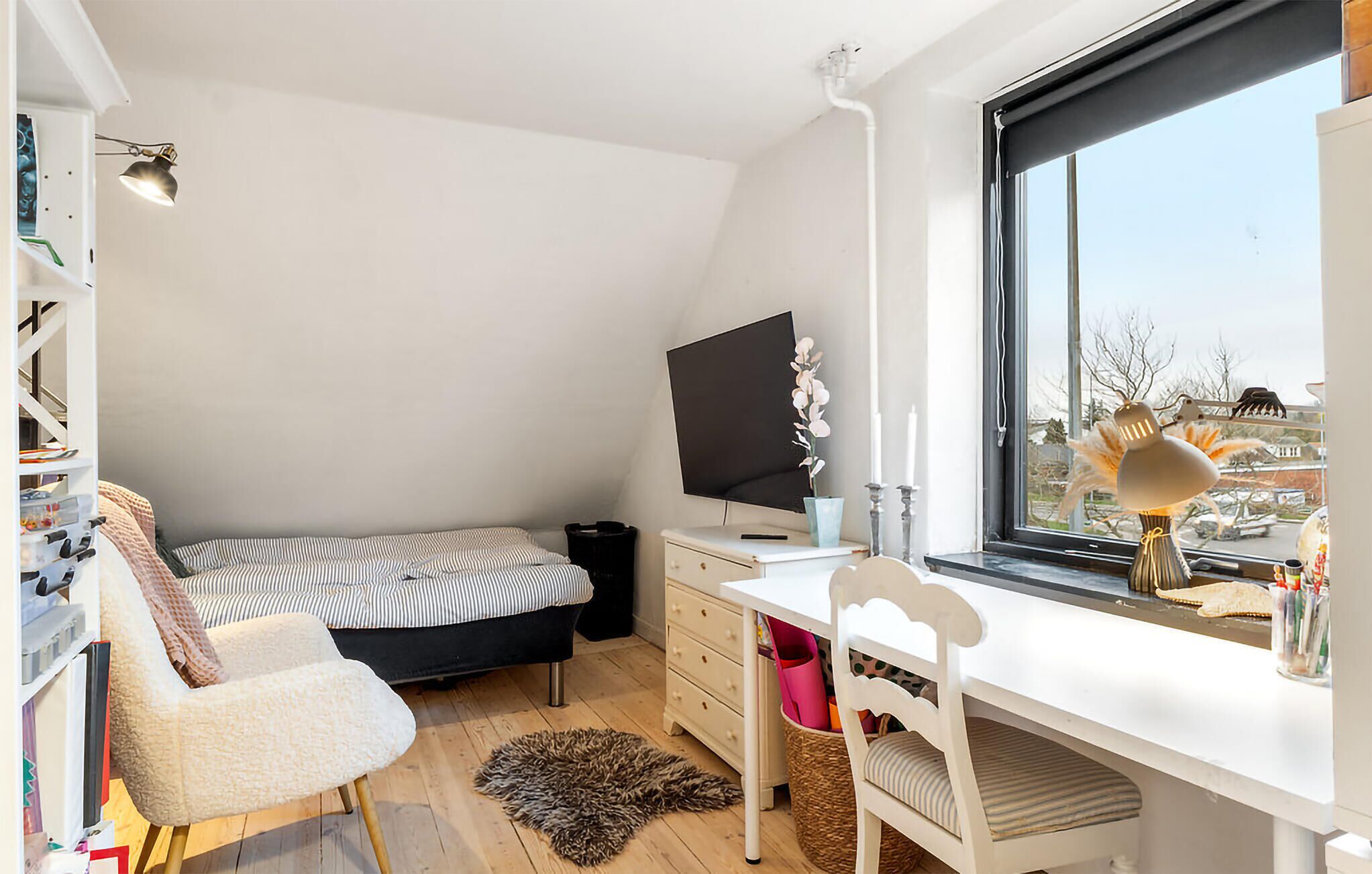 Ein Schlafsaalzimmer mit Bett, Schreibtisch, Stuhl und einem Fenster mit Blick.