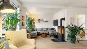 Una sala de estar acogedora con sofá, sillón y estufa de leña.