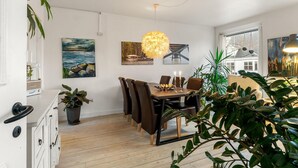 Un comedor con una mesa de madera, sillas y una lámpara colgante.