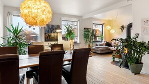 Una sala de estar moderna con comedor, ventanas amplias y plantas de interior.
