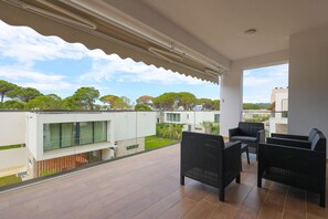 A balcony with outdoor furniture, a view of greenery and buildings, and a clear sky. - Sanpietro Vacation Apartment 012 (Ishëm)