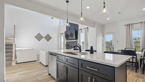 A modern kitchen with a large island, dark cabinetry, and pendant lighting. - Fort Haven Near Fort Campbell, Spacious 4BR Retreat (Clarksville)