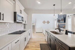 Une cuisine moderne avec des meubles blancs, une cuisinière noire et un plancher en bois.
