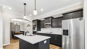 A modern kitchen with dark cabinets, stainless steel appliances, and a central island.