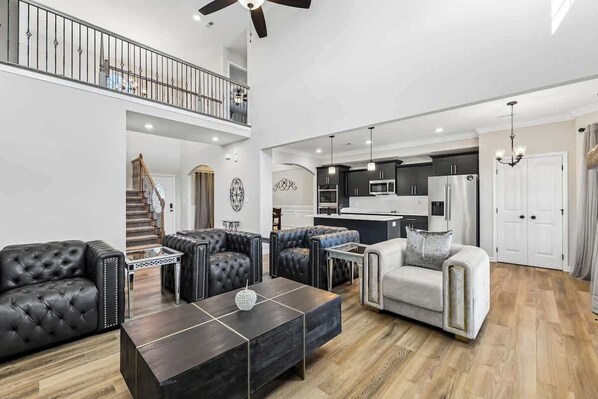 Un vaste espace de vie comprenant une cuisine moderne, un escalier et un balcon.