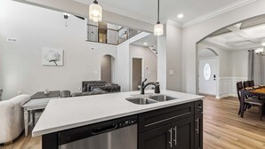 A modern kitchen with a central island, stainless steel appliances, and pendant lighting.