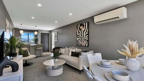 A modern living room with a sofa, coffee table, and dining area.