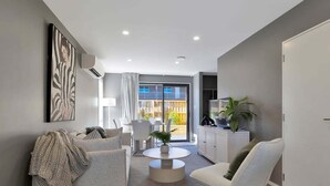 A modern living room with a sofa, armchair, and a round coffee table.