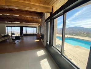 Ein großzügiger Wohnbereich mit einem großen Fenster mit Blick auf einen Pool und Berge.