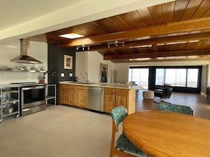Eine moderne Küche mit Holzschränken, Edelstahlgeräten und einem Essbereich mit Holztisch und Stühlen.