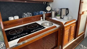 A compact kitchenette with a stove, sink, and storage cabinets.
