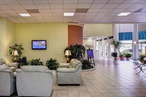 Eine Lobby mit Sitzgelegenheiten, einem Fernseher und Topfpflanzen.