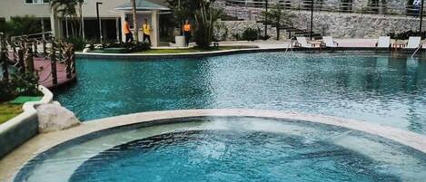 Una piscina con jacuzzi, un edificio moderno y palmeras.