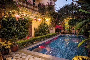 A pool area with a tiled floor, potted plants, and string lights. - Tam Coc Viet Ha Homestay (Nam Hoa Lu)
