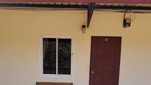 A wooden bench outside a building with a window and a door. - Phum Riang House (Chaiya)