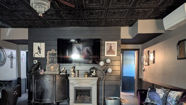 Una sala de estar con chimenea, televisor y sofá.