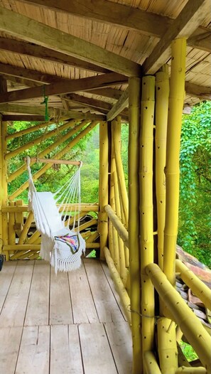 Ein Hängestuhl auf einer Holzterrasse mit Bambusgeländern.