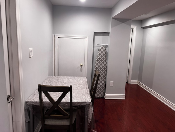 Un pasillo estrecho con una puerta al final, una mesa con mantel estampado y una silla.