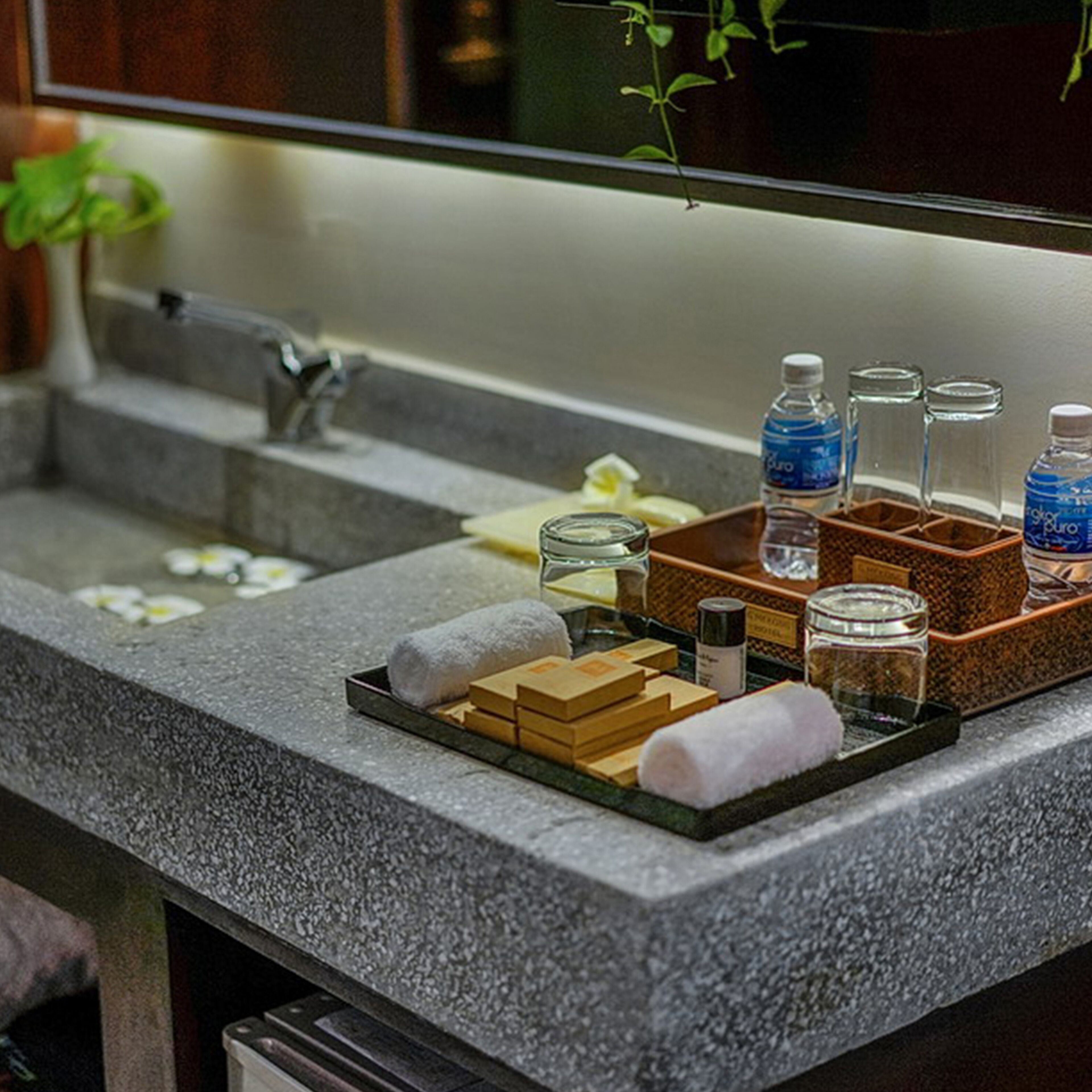 A bathroom with a granite countertop, a mirror, a sink, and toiletries.
