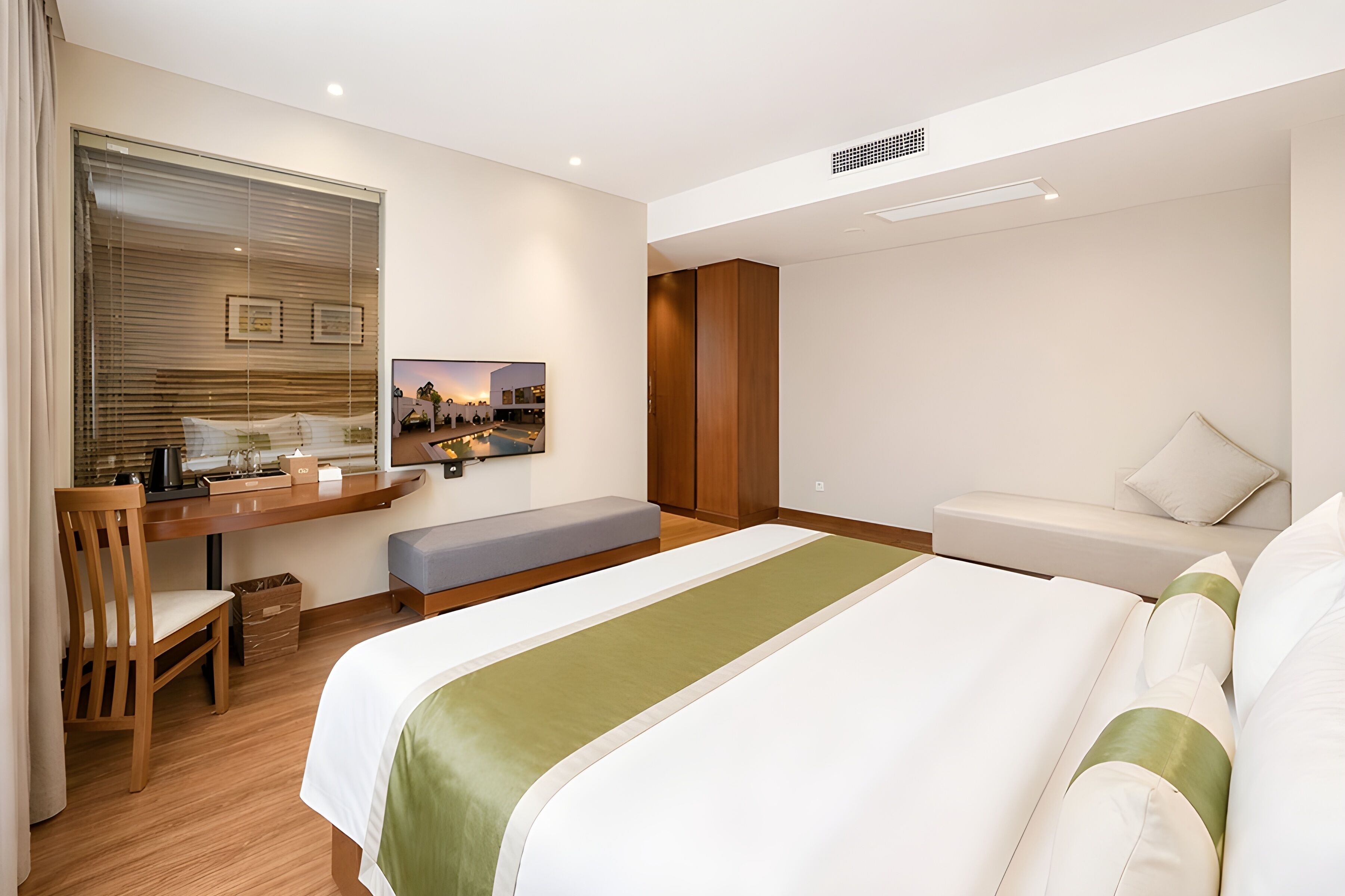 Una habitación de hotel con cama, escritorio, silla, sofá y ventana con persianas.