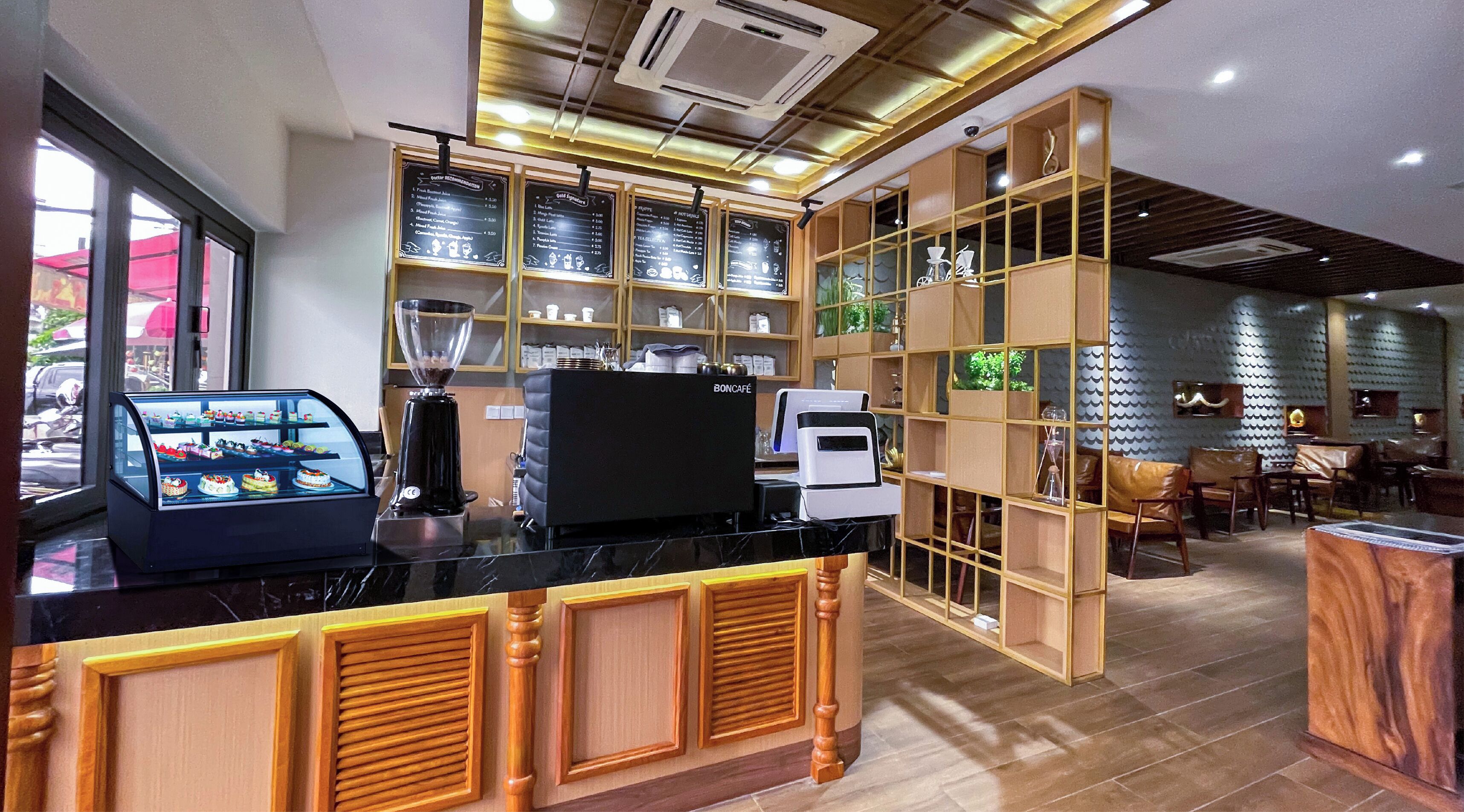 A café interior with a display case of pastries, a coffee machine, and a menu board.
