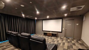 Une salle de cinéma privée dotée d’un grand écran, de fauteuils inclinables en cuir et d’un sol recouvert de moquette.